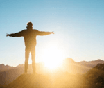 a man watching sunrise from top of mountain