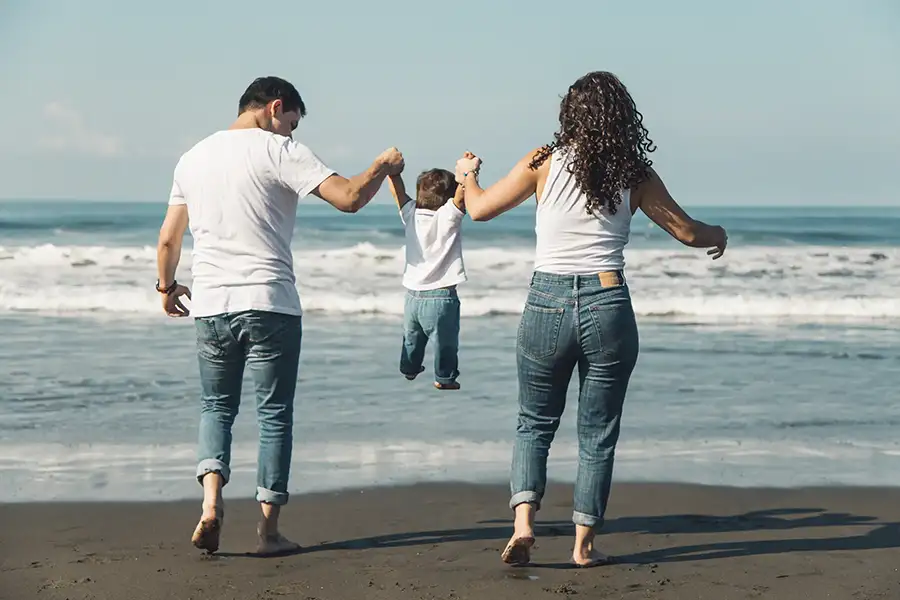 happy parents throwing their baby sunny beach